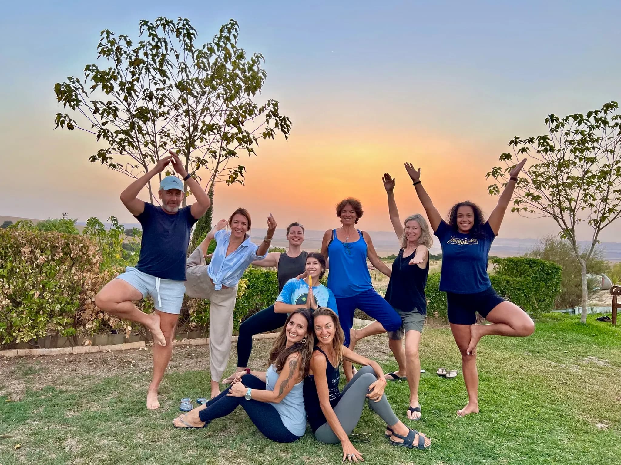 A group posing at sunset, the sky orange behind them.