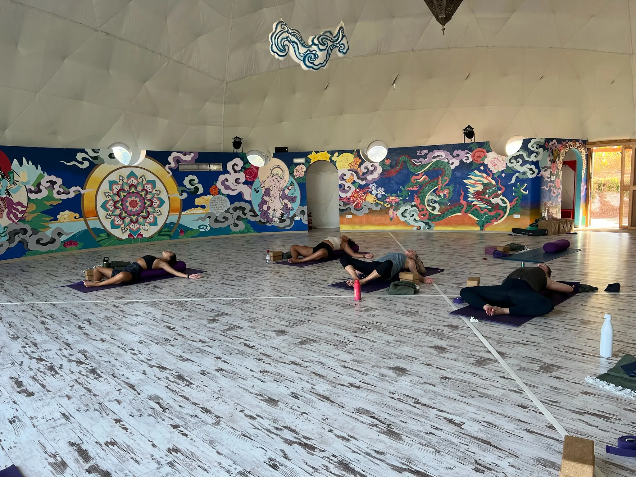 Savasana in a room with colorful murals on the walls.